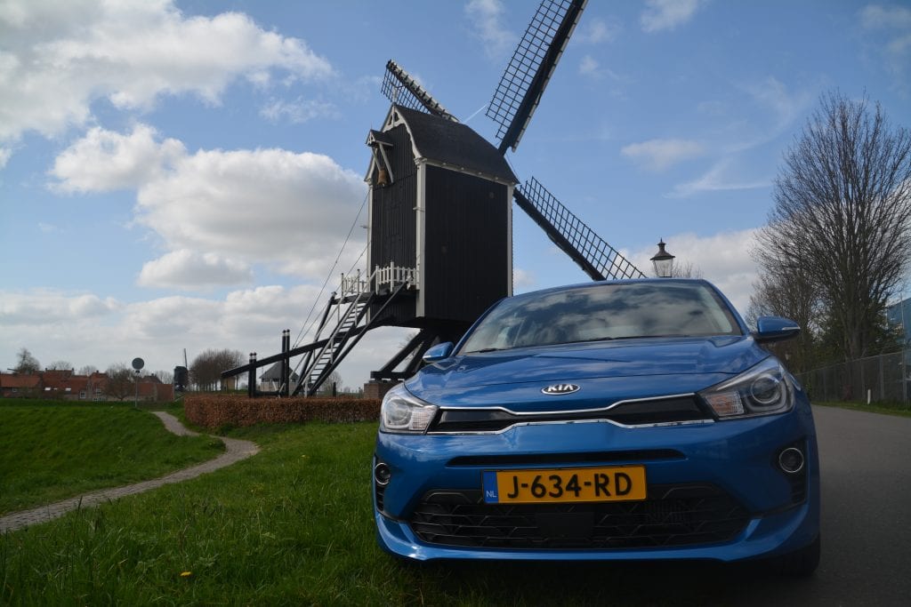 neus blauw Kia Rio met molen op de achtergrond