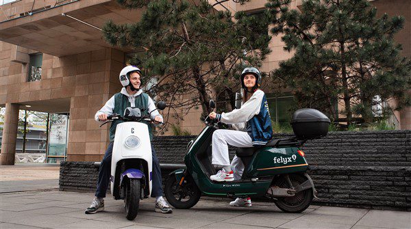 groene en witte scooter met twee jongeren
